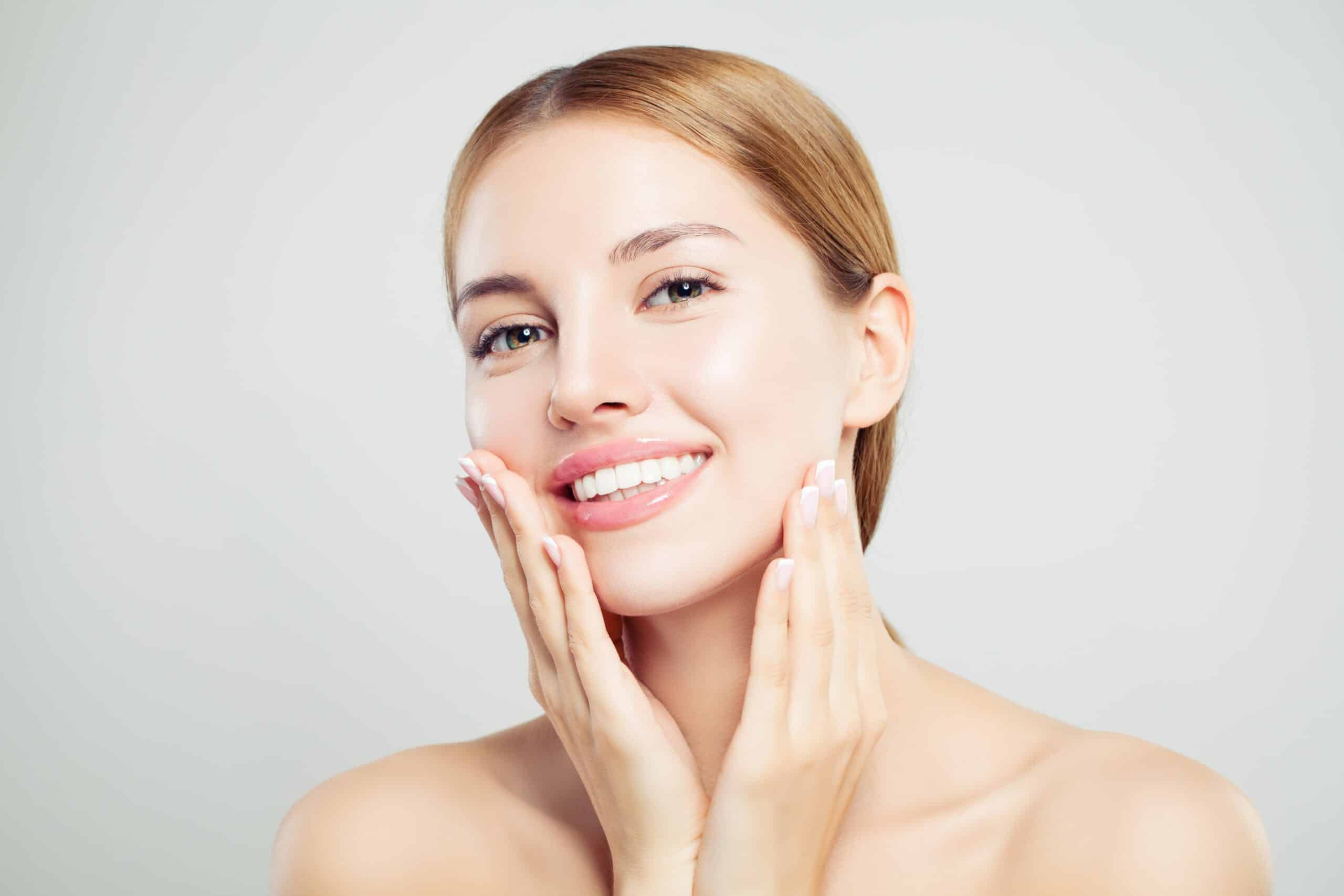 a woman touching her face | synergy wellness and medispa